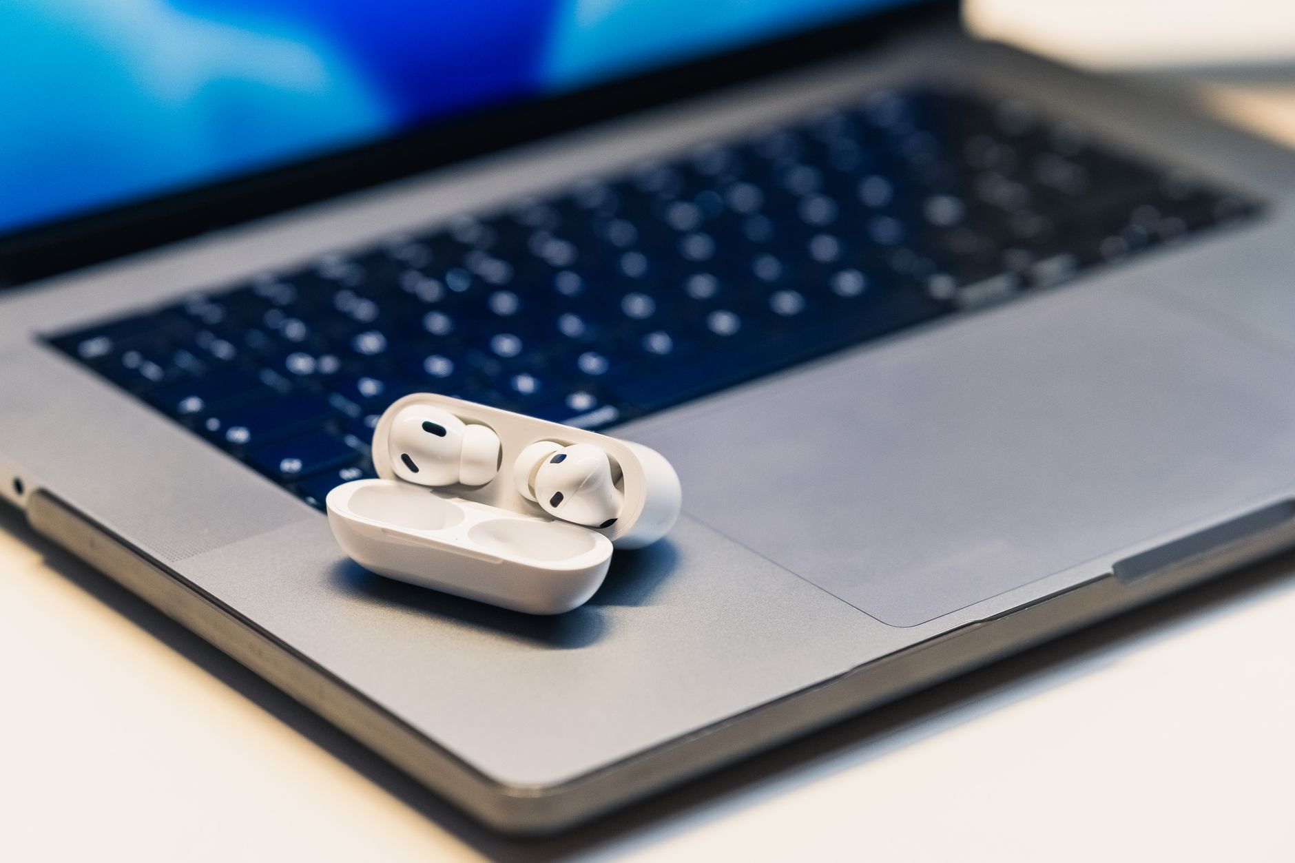 Two Bluetooth headphones beside a Windows laptop